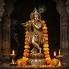 Handcrafted Krishna murti playing a bamboo flute in a mandir niche with diyas and marigolds