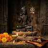 Handcrafted Shiva murti with trishul and crescent moon beside a diya and marigolds