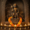 Hanuman murti with gada and seven lit diyas in a mandir