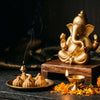 Stylish modern matte gold Ganesha murti with modaks and diya in a home mandir