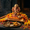 Handcrafted Ganesha murti surrounded by lit diyas and marigold flowers for Diwali